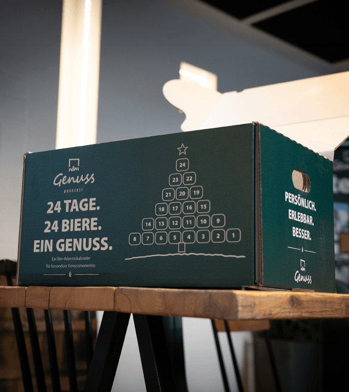 Bier Adventskaldender in grünem Paket auf Tisch platziert.