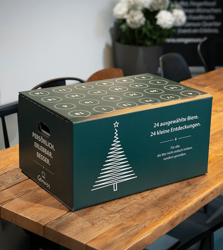 Bier Adventskaldender in grünem Paket auf Tisch platziert.