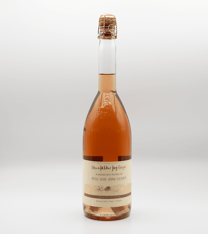 Bunte Flasche mit rosafarbenem alkoholfreiem Frizzante, mit Etikett in Creme, Gold und Schwarz, verschlossen mit Korken.