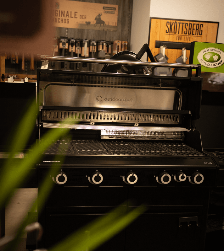 Outdoorchef HEAT 545 Gasgrill mit geöffneter Grillhaube, Grillrost in Schwarz.