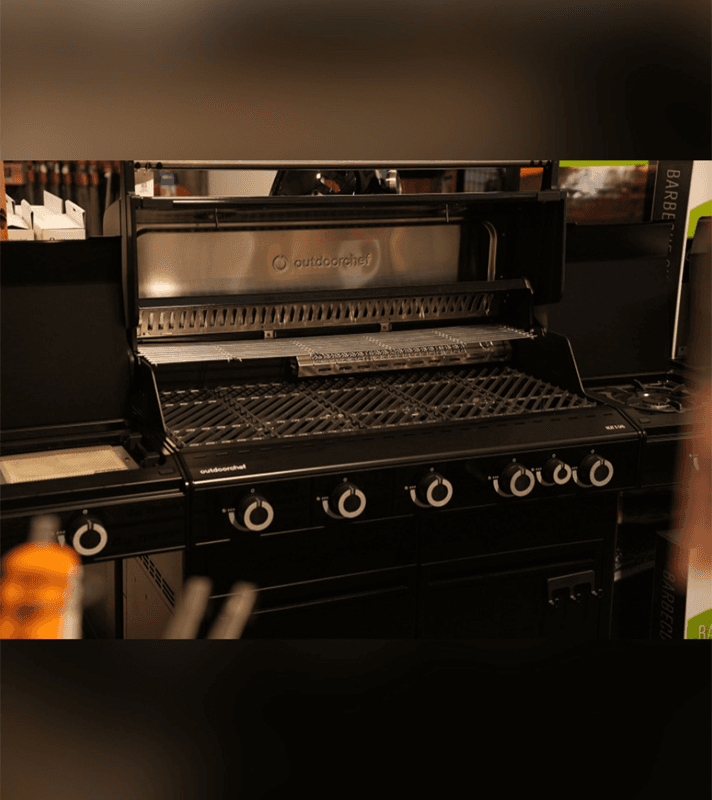 Outdoorchef HEAT 545 Gasgrill mit geöffneter Grillhaube, Grillrost in Schwarz.